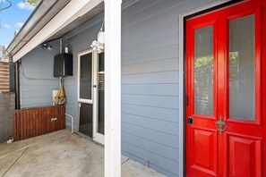 A house with a red door, a garage door, and a small porch area with a bench. - Stylish 2-bed Cottage in Trendy Erskineville (Sydney)