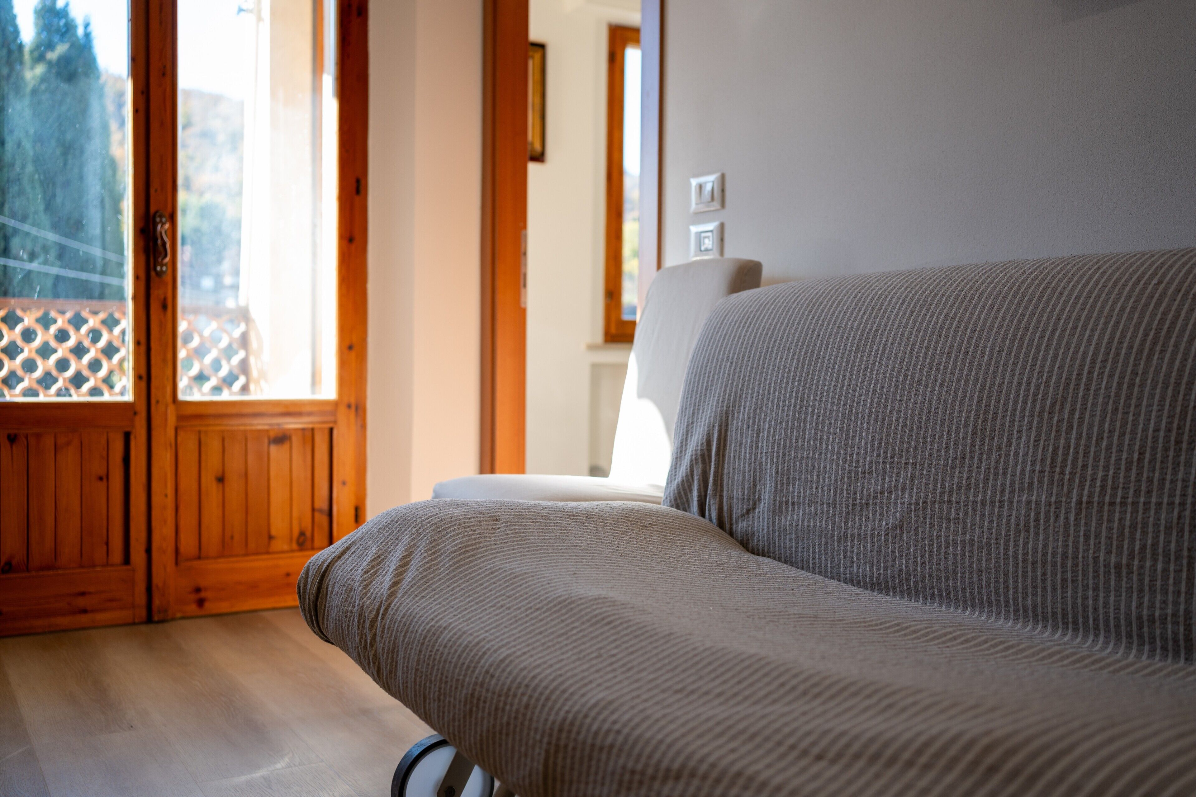 Una habitación con puerta de madera, un sofá y vistas por una ventana.
