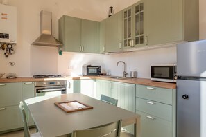 Une cuisine moderne avec des meubles de couleur vert clair, des appareils en acier inoxydable et une table en bois.