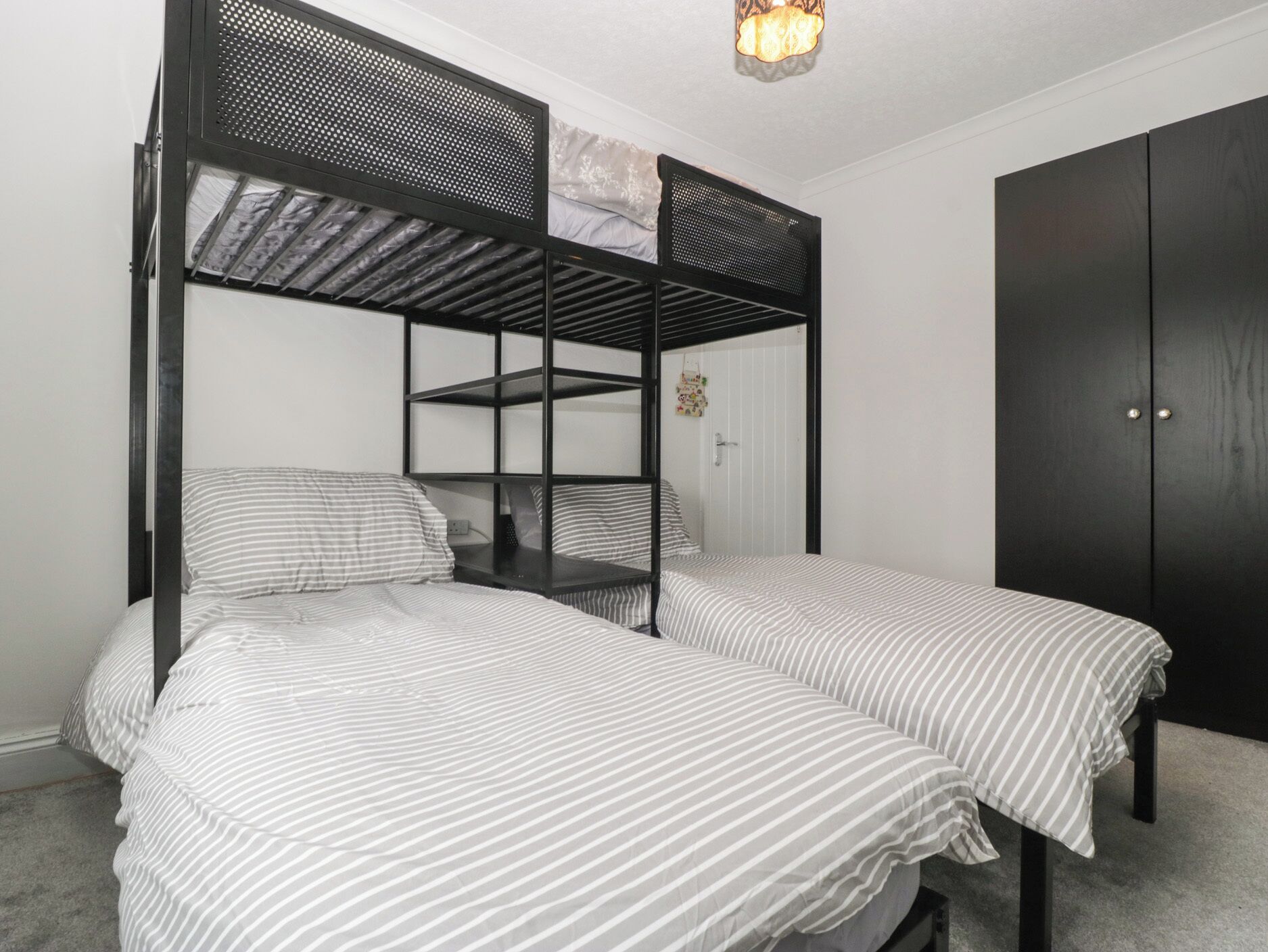 Habitación con literas, un armario y una lámpara en el techo.