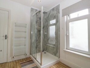 A modern bathroom with a glass-enclosed shower, a white door, and a window. - Lush House (Barry)