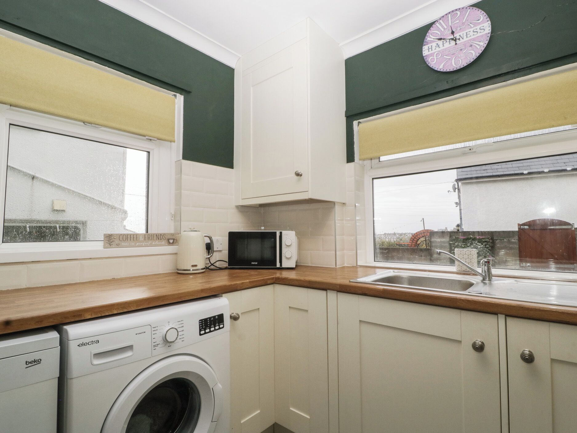 A compact kitchen with a washing machine, microwave, and a coffee maker on the counter.