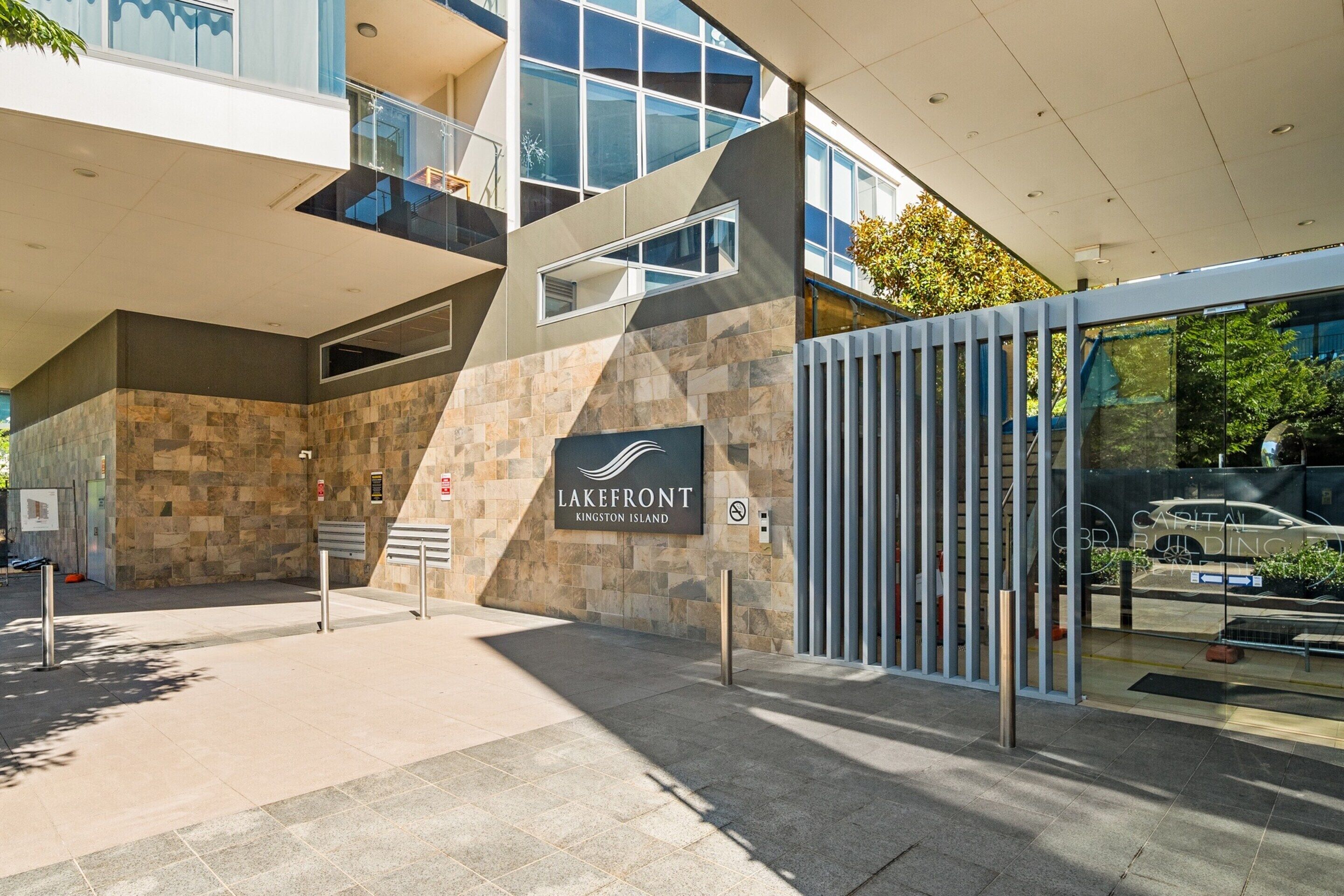 A modern building entrance with a stone facade, a glass door, and a sign reading 'Lakefront Kingston Island.'