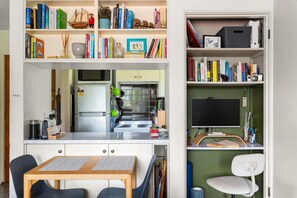 Una cocina compacta con comedor, una estantería empotrada y un pequeño espacio de trabajo.