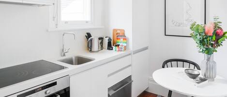 A modern kitchen with white cabinets, a black countertop, a built-in oven, and a window above the sink.
