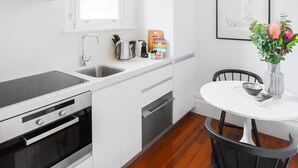 Une cuisine moderne avec des meubles blancs, un four encastré, un évier et une fenêtre.