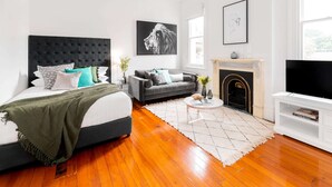 Une chambre moderne avec un grand lit, un canapé gris, une cheminée et un téléviseur.