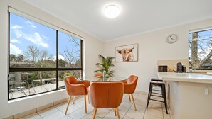 Una cocina moderna con comedor, ventanas amplias y un reloj en la pared.