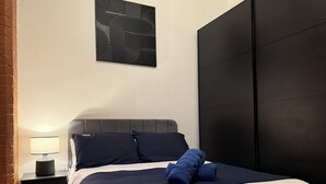 A bedroom with a bed, a nightstand, a lamp, and a wall art piece.