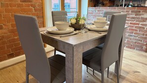 A dining area with a brick wall, a window, and a kitchen in the background.