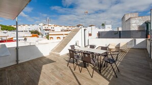 Eine Dachterrasse mit Tisch und Stühlen, einer Treppe und Blick auf umliegende Gebäude.
