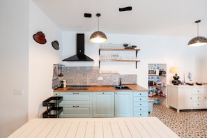 Una cocina con armarios azul claro, una campana extractora negra, encimera de madera y un salpicadero con diseño.