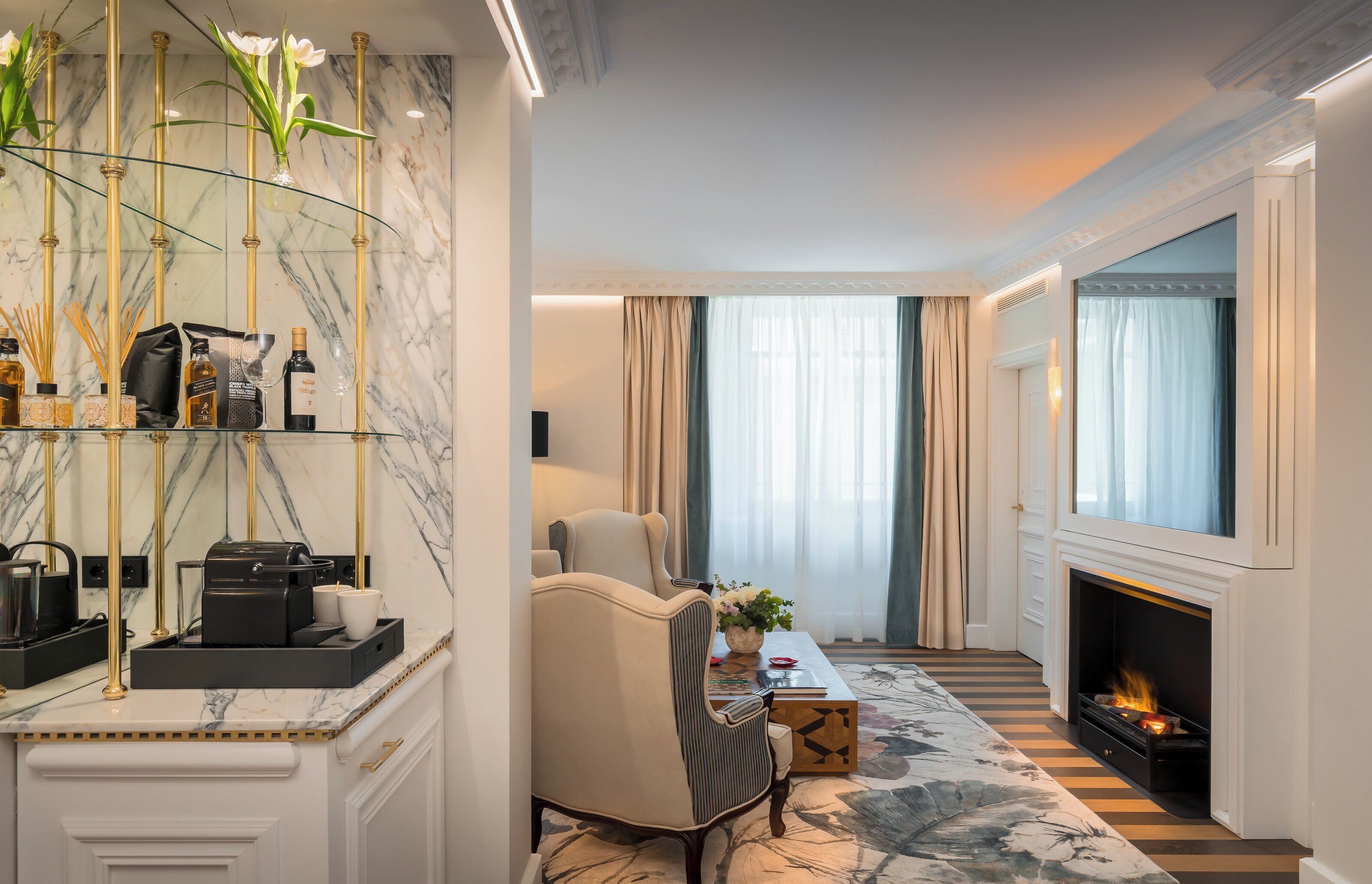 A modern hotel room with a marble wall, a sofa, a fireplace, and a coffee table.
