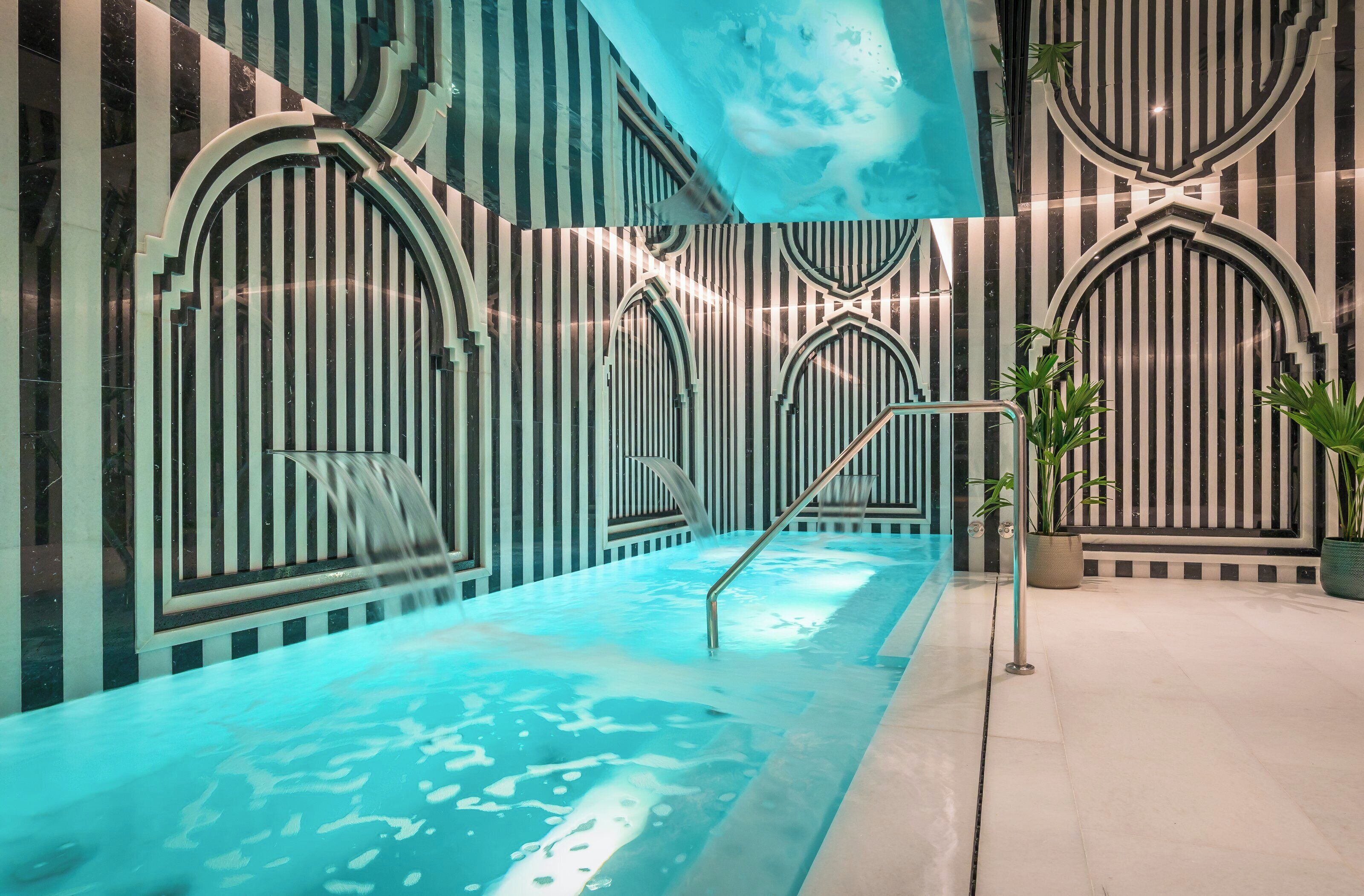 A modern indoor pool with striped walls and arched doorways.