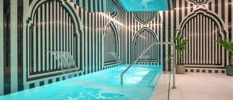 En moderne swimmingpool indendørs med stribede vægge og buede indgange.