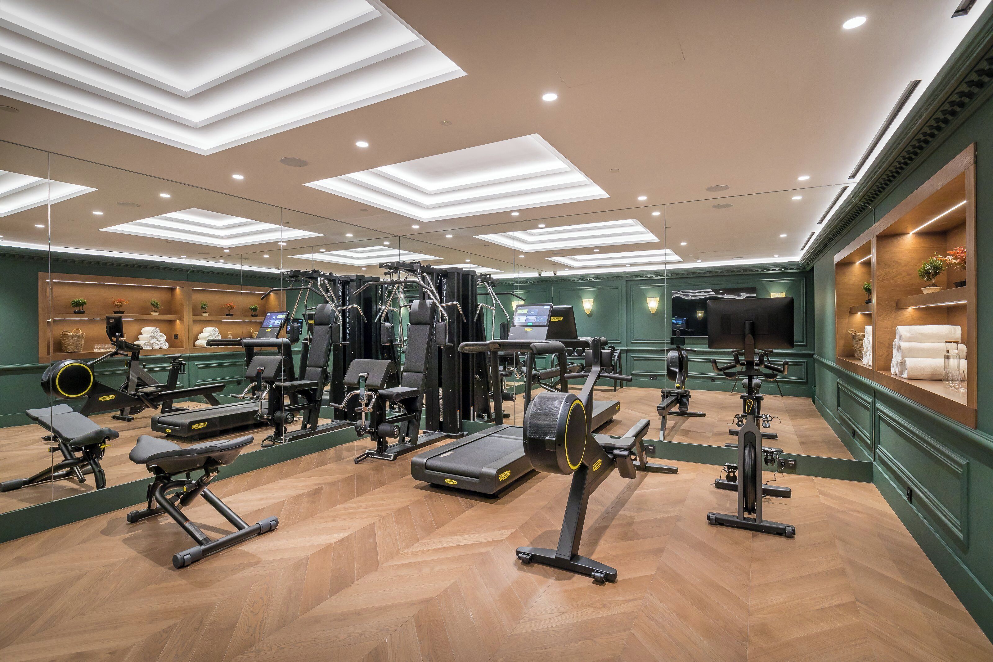 Een sportschool met trainingsapparatuur, spiegels en een houten vloer.