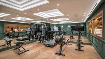 A gym with exercise equipment, mirrors, and a wooden floor.