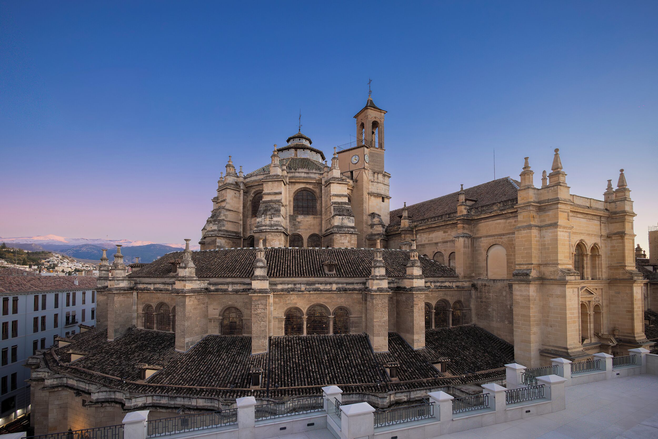 A historic building with a large central dome, a bell tower, and a courtyard with seating.