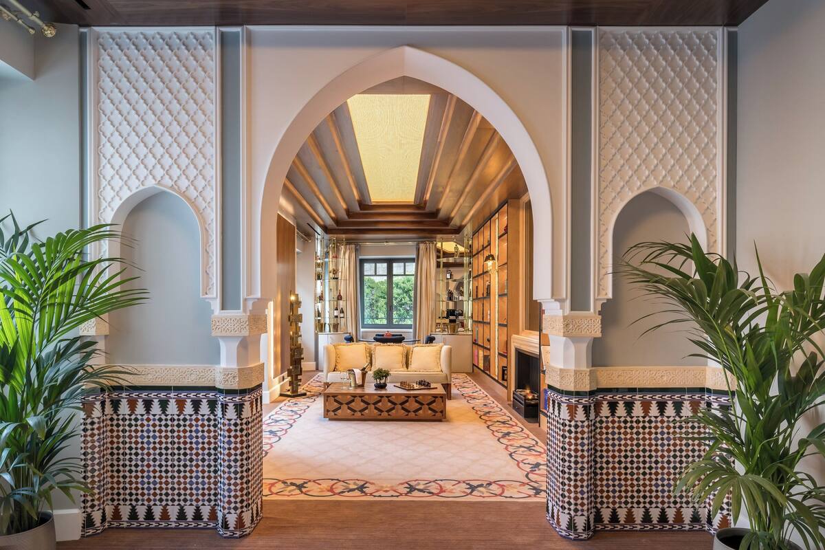 An arched hallway with a patterned floor, a central seating area, and a fireplace.