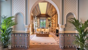An arched hallway with a patterned floor, a central seating area, and a fireplace.