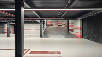 A multi-level parking garage with red and white striped walls, metal pillars, and overhead lighting.