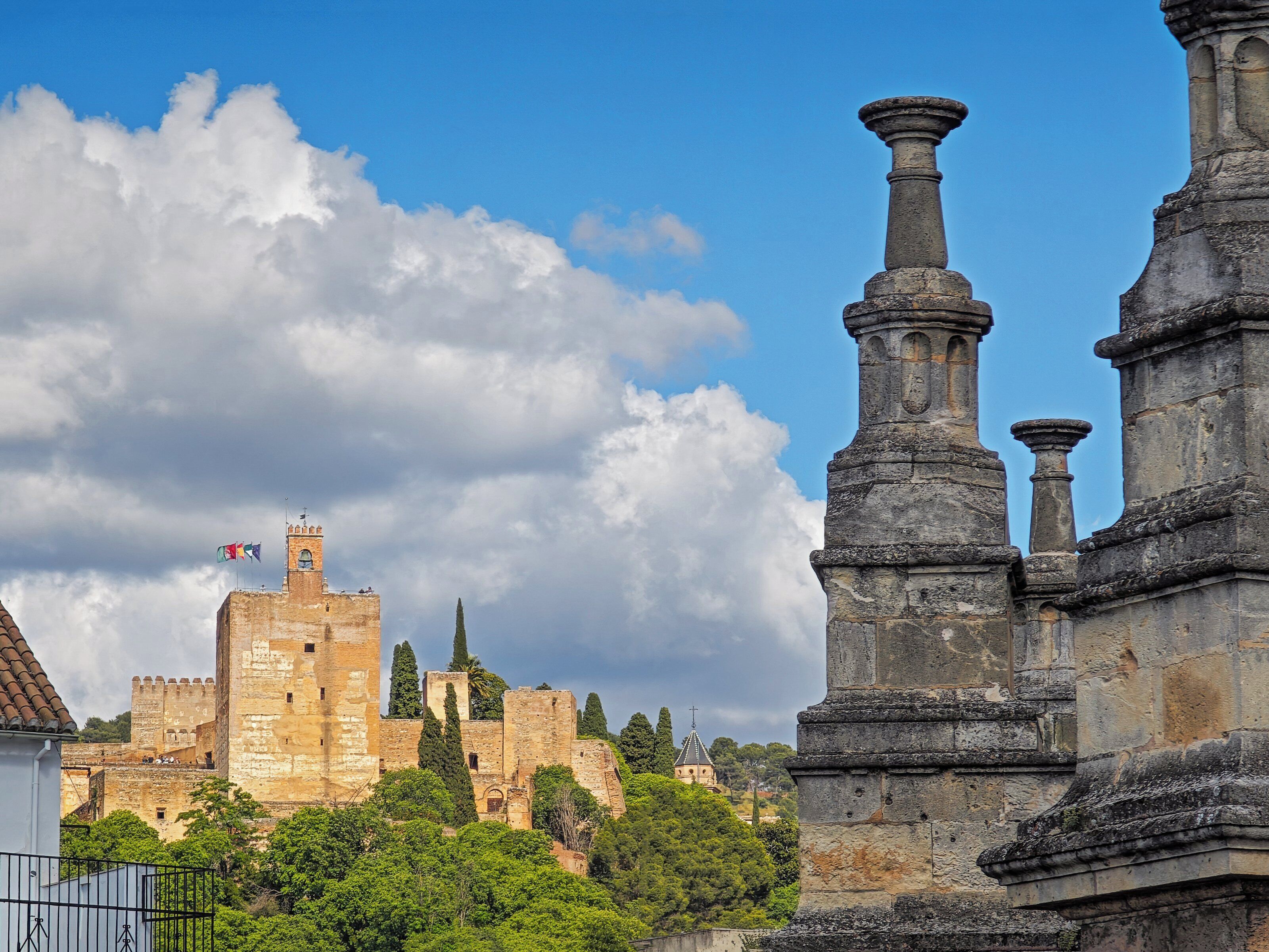 A historic stone structure with columns, a castle in the background, and lush greenery.