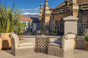A terrace with two wicker chairs, a small table with wine glasses, and a potted plant. - Gran Hotel Claridge Granada - Preferred Hotels & Resorts (Granada)