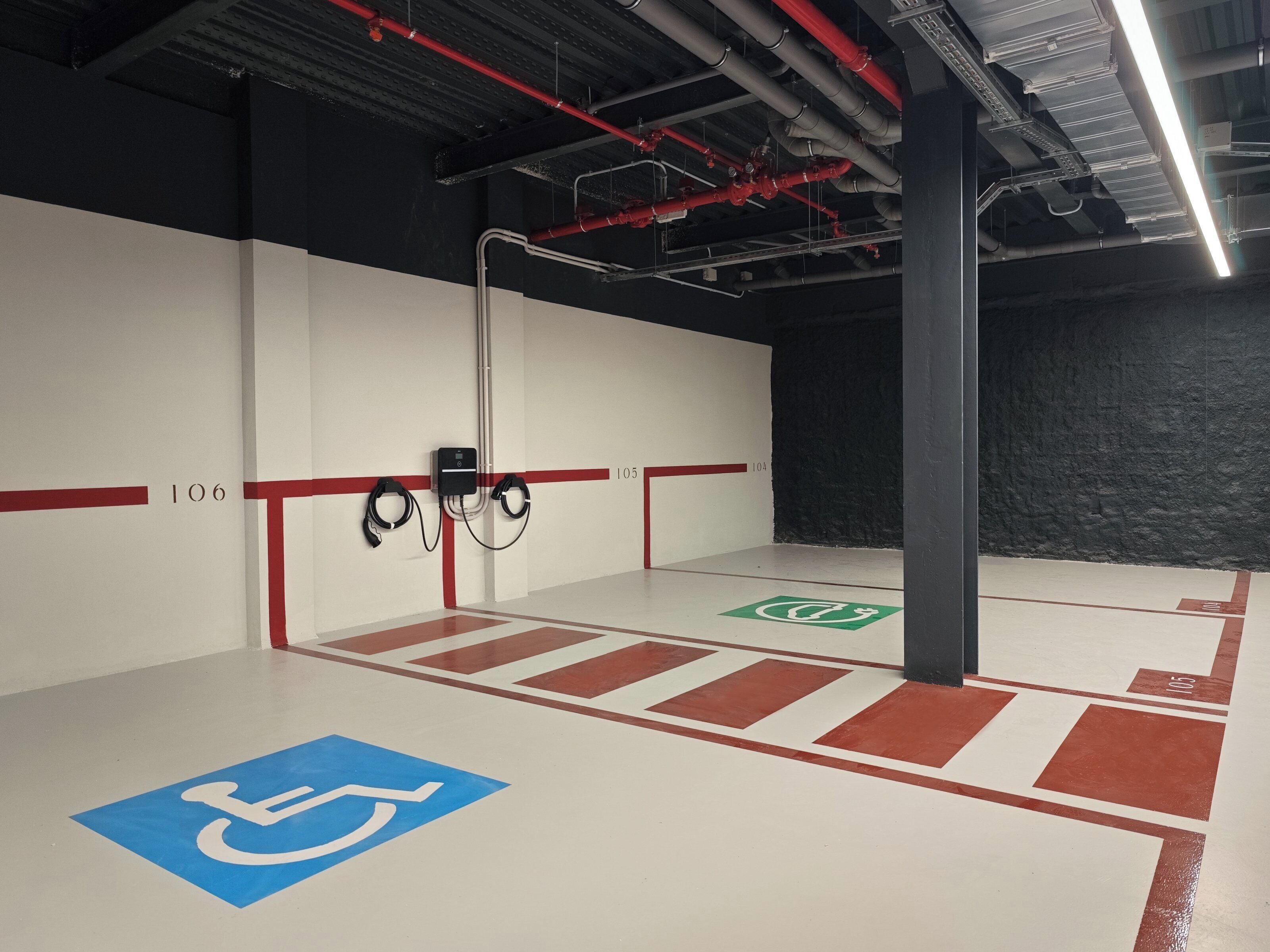 A parking garage with clear signage, including a wheelchair-accessible area, and a fire hose reel mounted on the wall.