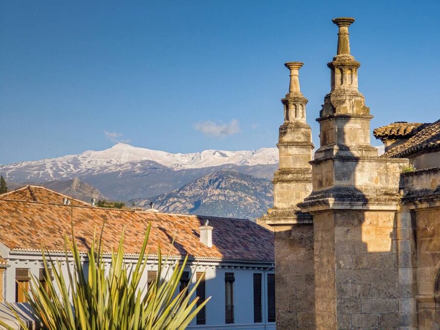 Un bâtiment doté de colonnes en pierre, avec une chaîne de montagnes en arrière-plan.