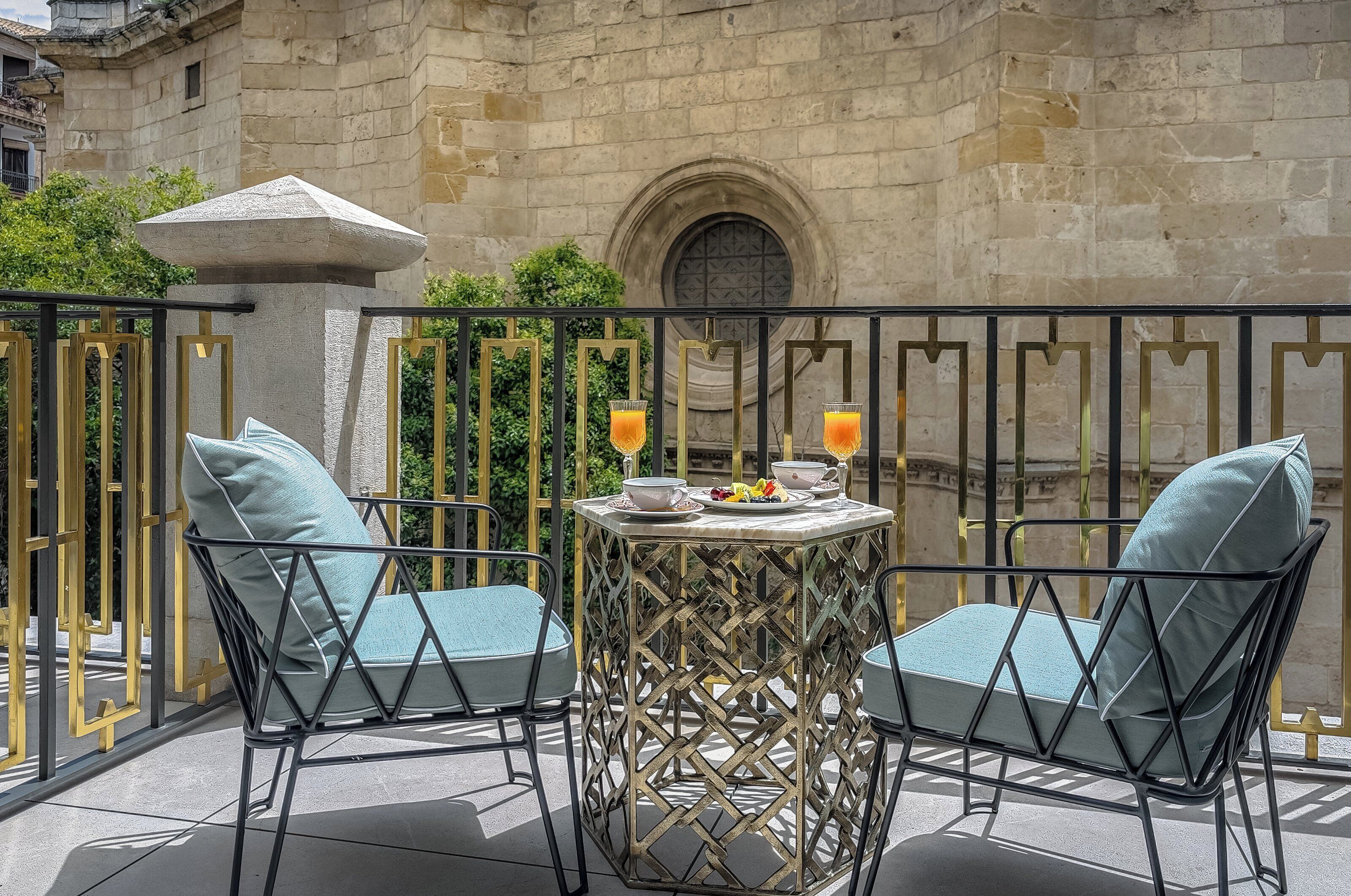 A balcony with two chairs, a table, and a stone structure.