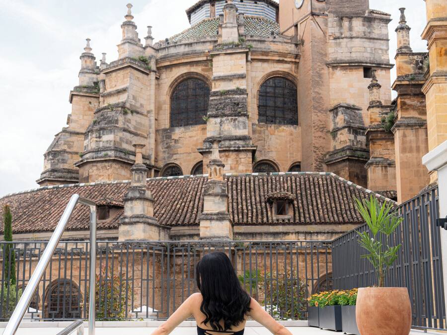 Una mujer en una piscina, con un edificio histórico al fondo.