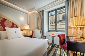 A hotel room with a large bed, a chair, a small table, and a window with a view of a building. - Gran Hotel Claridge Granada - Preferred Hotels & Resorts (Granada)