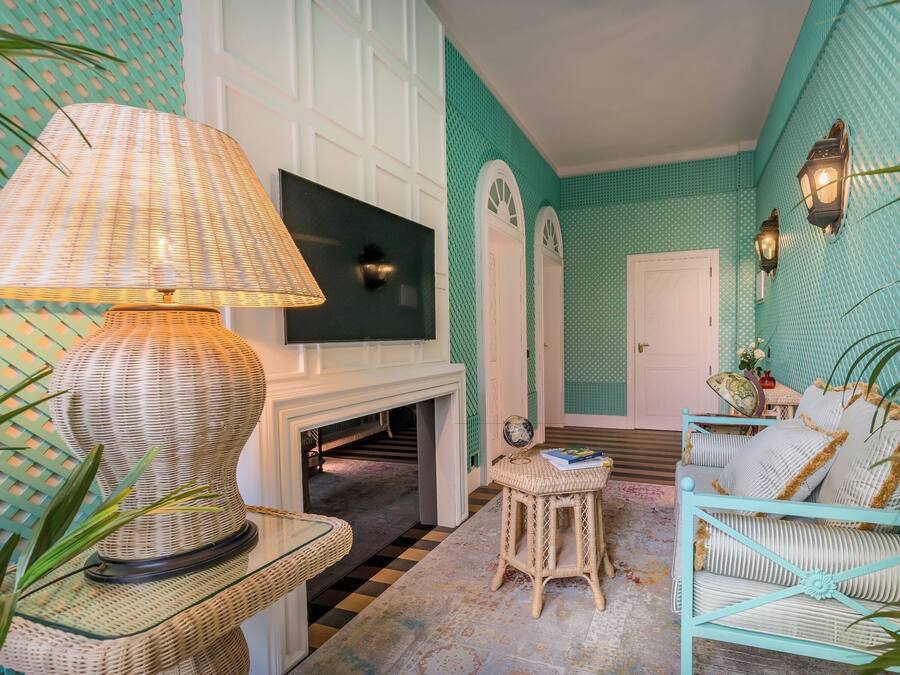 A room with a television, wicker furniture, and a patterned wall.