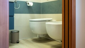 A bathroom with a toilet, bidet, and trash can. - Room in the Heart of Val d'Orcia with Balcony and Wi-Fi (Montepulciano)