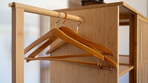 A wooden wardrobe with a hanging rod and a single wooden hanger. - Room in the Heart of Val d'Orcia with Balcony and Wi-Fi (Montepulciano)