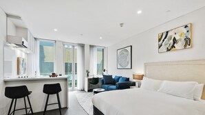 Une chambre d’hôtel moderne avec un grand lit, un bureau avec deux chaises, un canapé et un tableau au mur.