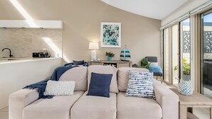 A modern living room with a sofa, a coffee table, a lamp, and a painting on the wall. - 3-bed With Beach Views and Entertainment Area (Denhams Beach)
