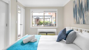 A bedroom with a bed, a window with a view of greenery, and a white bedside table. - 3-bed With Beach Views and Entertainment Area (Denhams Beach)