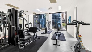 Een moderne sportschool met diverse fitnessapparaten, grote ramen en uitzicht op de stad.