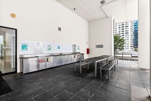 Een modern interieur met een lange toonbank, een bankje en uitzicht op een gebouw door een raam.