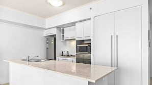 Een moderne keuken met witte kasten, een granieten aanrechtblad, roestvrijstalen apparatuur en een inbouwoven.