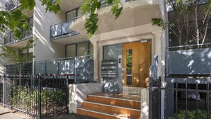 A modern building with a wooden door, a staircase leading to the entrance, and a metal fence. - Central 2-bed Pad With Tennis Court, (Melbourne)