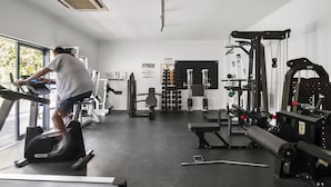 A gym with cardio equipment, weight machines, and a bench. - Central 2-bed Pad With Tennis Court, (Melbourne)