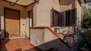 A residential entryway with a wooden door, a potted plant, and a staircase leading to an upper level. - Terrazza sul mare (Santa Maria di Castellabate)