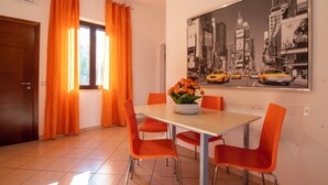 A dining area with a table, orange chairs, and a flower centerpiece. - Terrazza sul mare (Santa Maria di Castellabate)