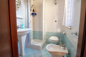 Une salle de bain équipée d’une douche, de toilettes, d’un lavabo et d’un miroir.