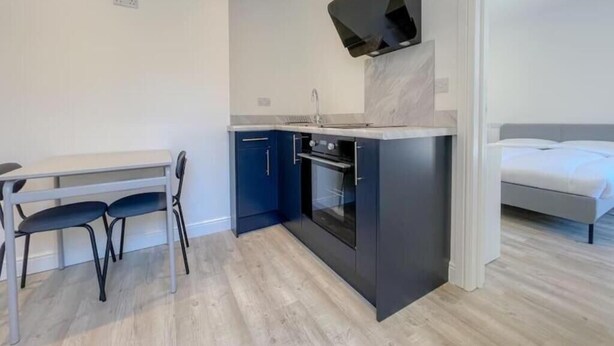A compact kitchen with dark cabinets, a built-in oven, and a modern stove. - Britannia Road. (Great Yarmouth)