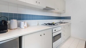 Una cocina moderna con armarios blancos, estufa a gas, lavaplatos y un tostador.