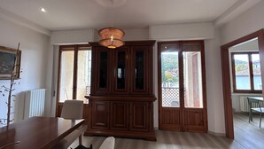 Ein geräumiges Zimmer mit einem Esstisch, einer großen Holzkommode und Blick durch die Tür.