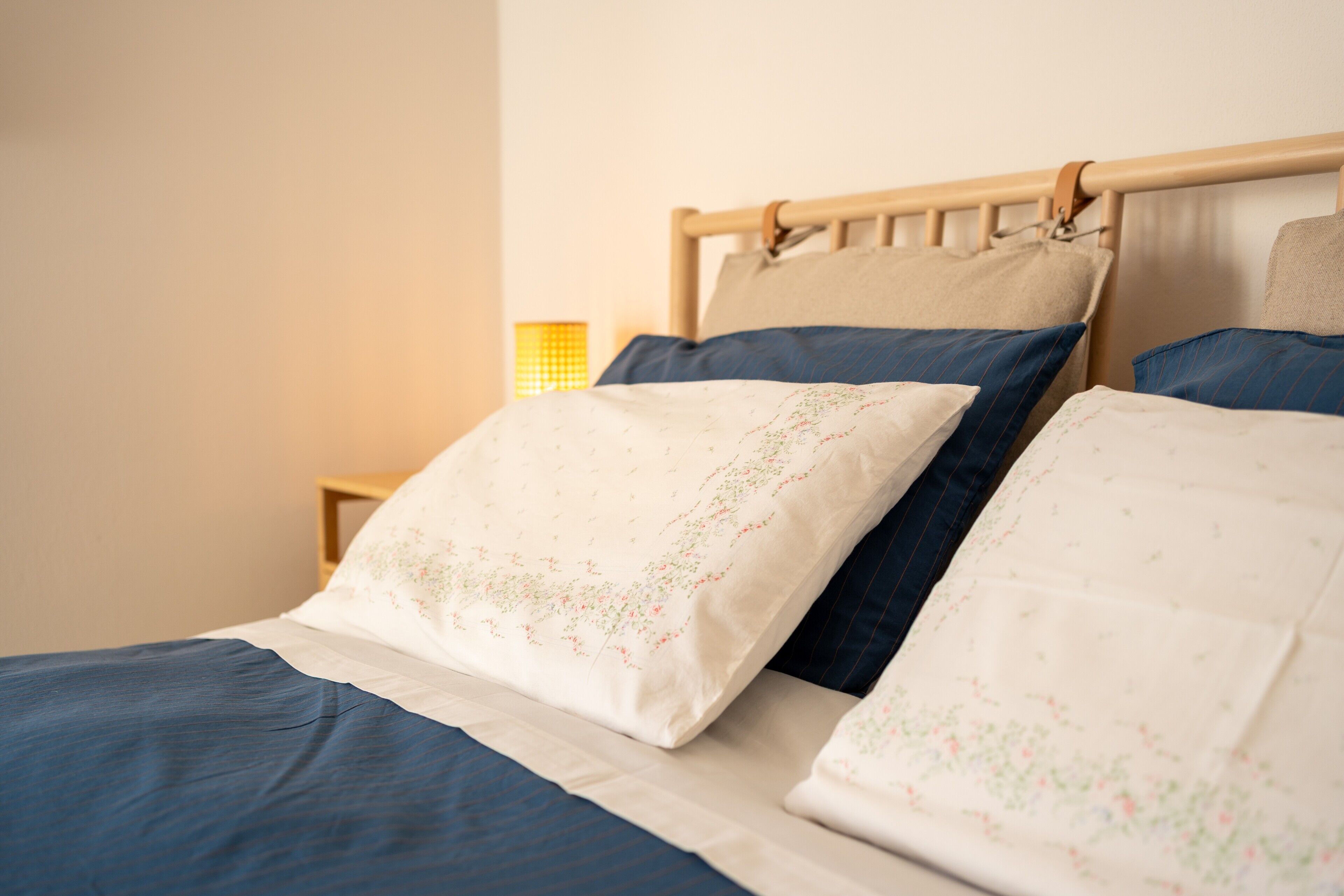 Un letto con testiera in legno, biancheria azzurra e un comodino con una lampada.